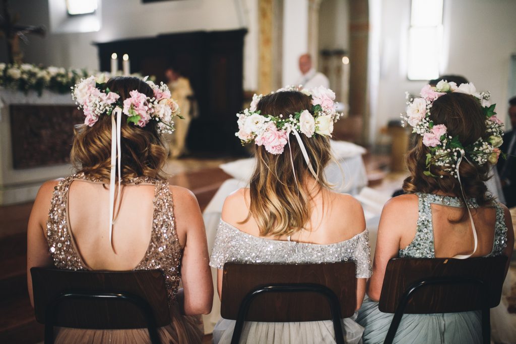 Look from behind at bridesmaids sitting on the chairs in the chu