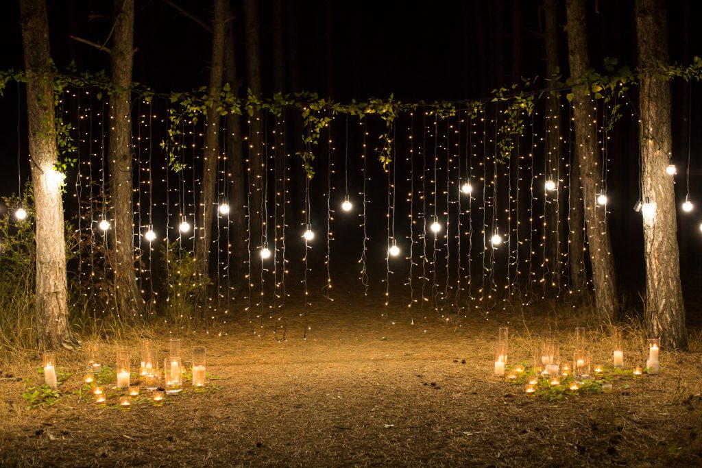 Wedding ceremony evening with candles and lamps in the coniferou